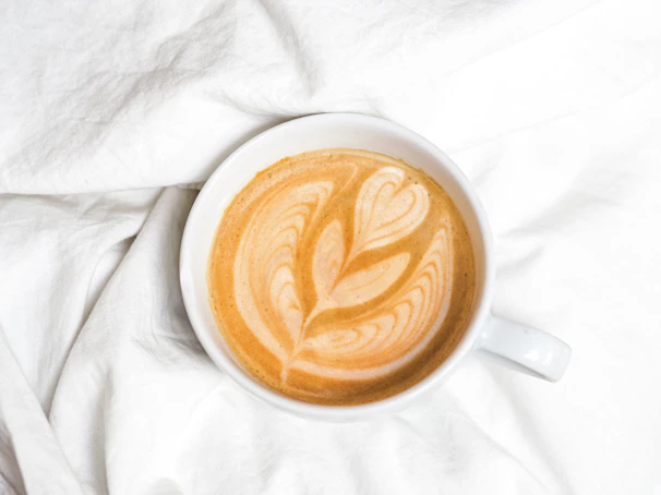 A barista carefully pouring latte art into a warm cup, sunlight streaming through a large window.