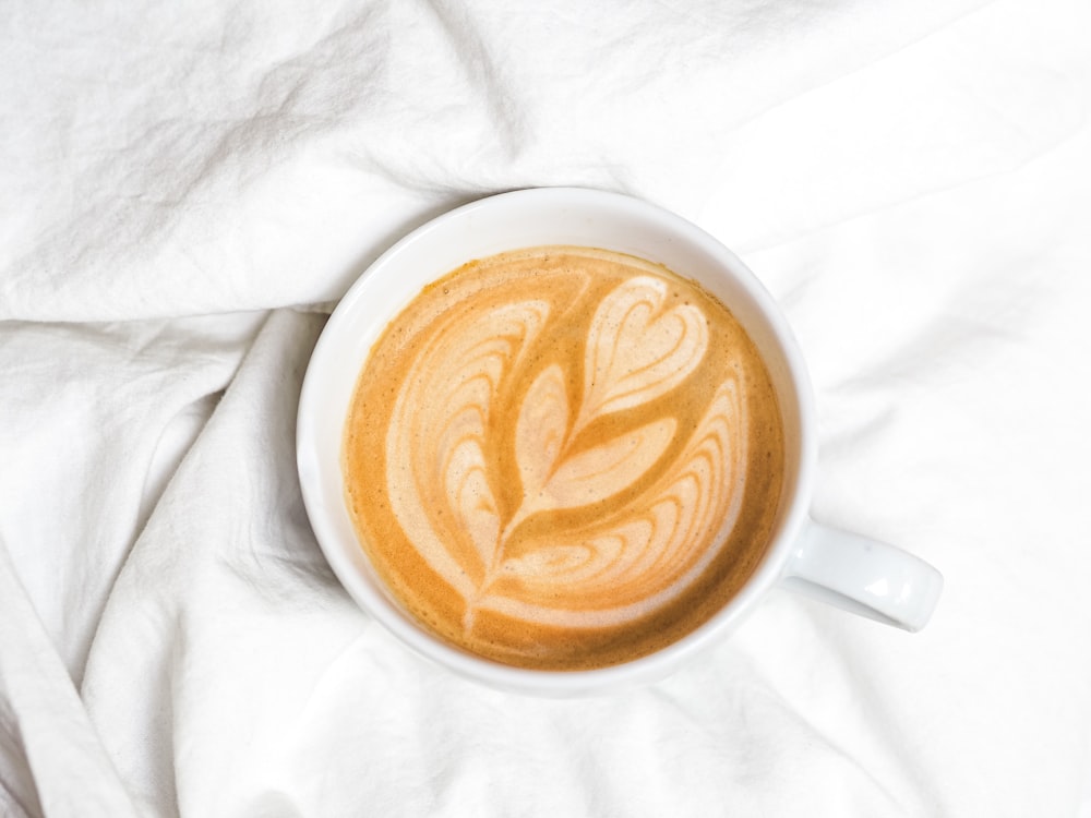 Taza de cerámica blanca con líquido marrón y blanco