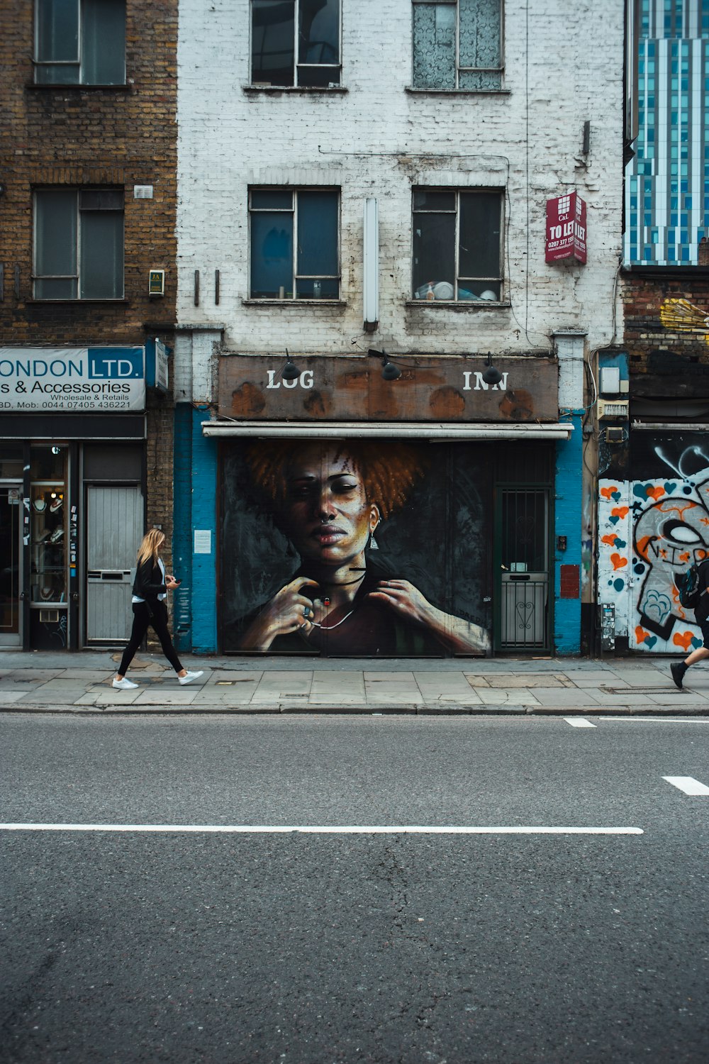 a woman walking down a street past a tall building