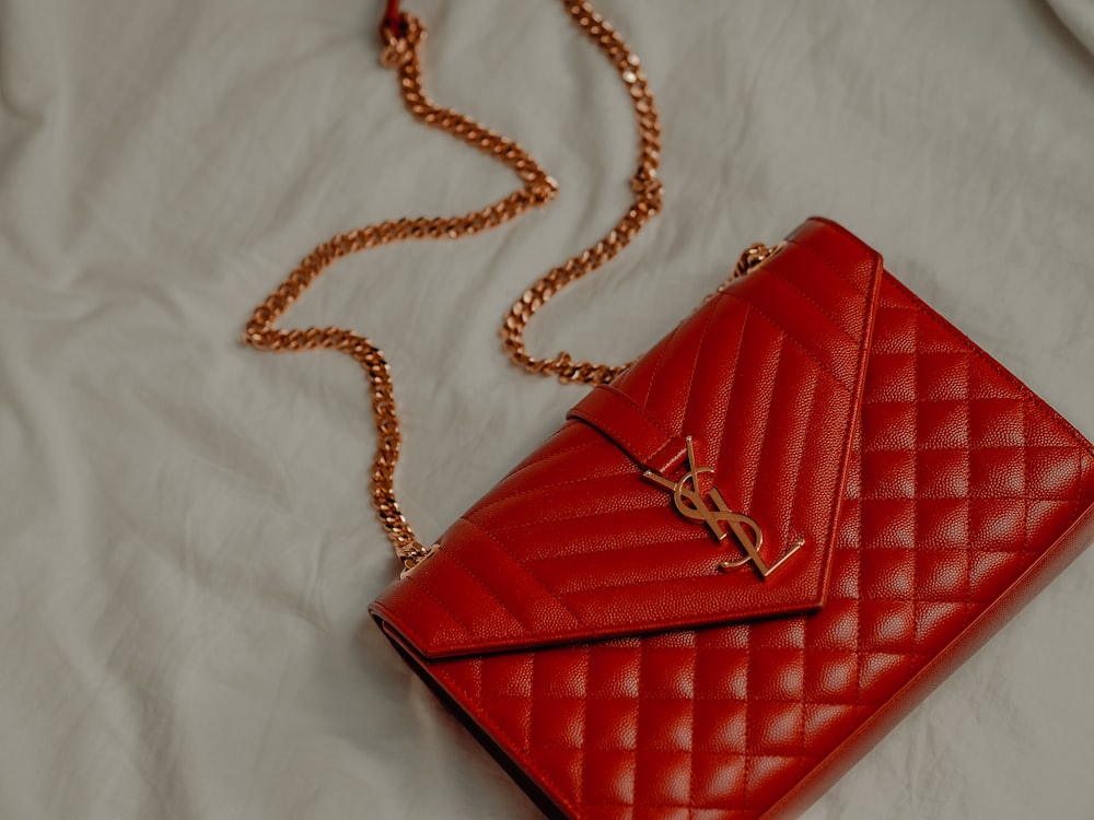 red leather sling bag on white textile