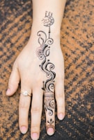 Wrist wrapped in a fine-line jagua henna design with petals and leaves.