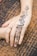 Close-up of a delicate henna tattoo design on a woman's hand at a festive event.