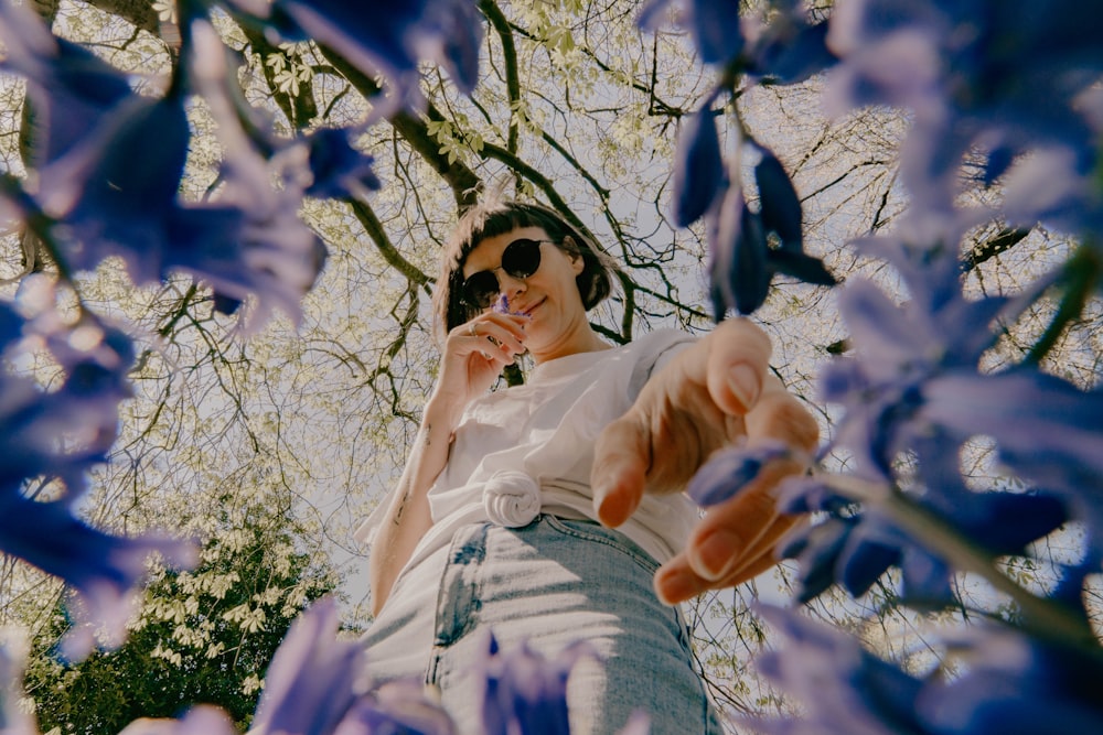 Femme en robe blanche sous un arbre à fleurs blanches pendant la journée