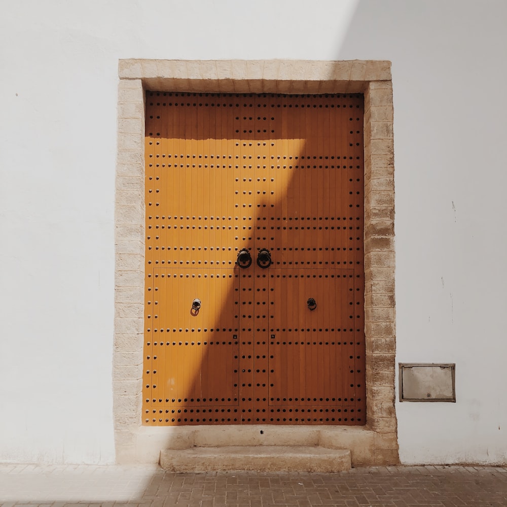 puerta de madera marrón sobre pared de hormigón blanco