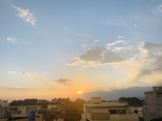 Sunset over a newly developed housing area with paved streets and streetlights.