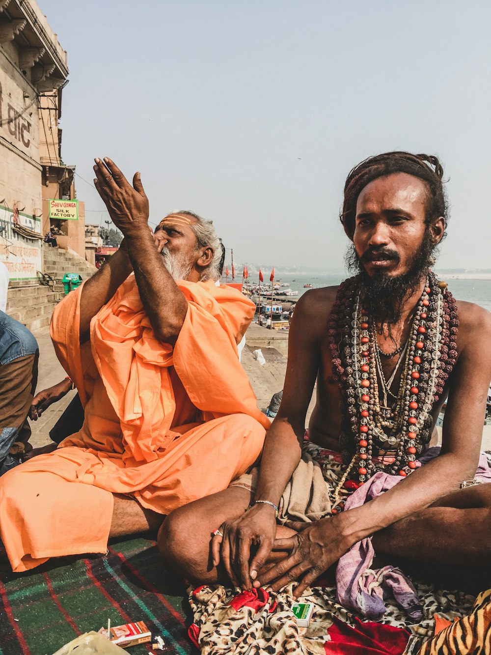 man in orange thobe sitting on brown wooden bench