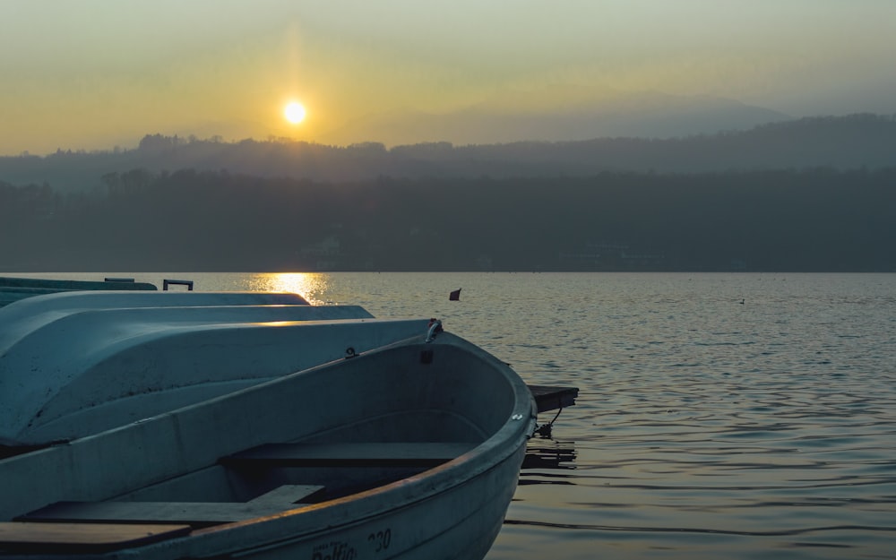 white and blue boat on sea during sunset