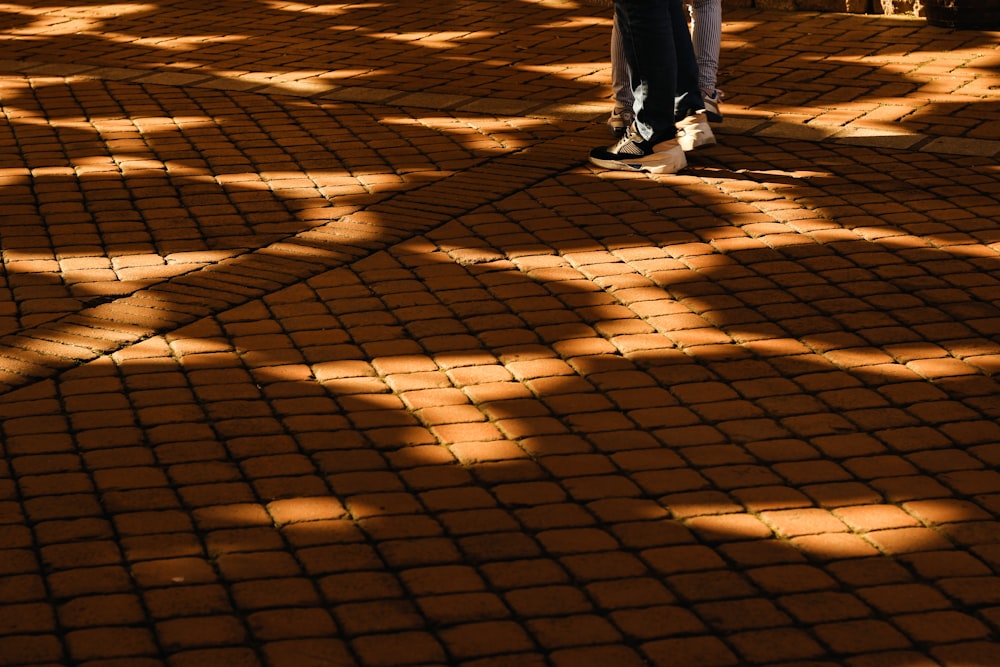 person in black pants and white sneakers standing on brown sand during daytime