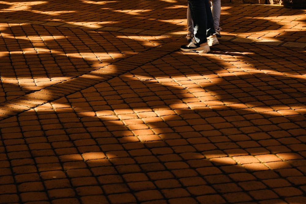 persona in pantaloni neri e scarpe da ginnastica bianche in piedi su sabbia marrone durante il giorno