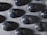 A collection of black marbles decorated with white specks resembling stars in a night sky, arranged neatly on a textured gray surface.