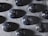 A collection of black marbles decorated with white specks resembling stars in a night sky, arranged neatly on a textured gray surface.