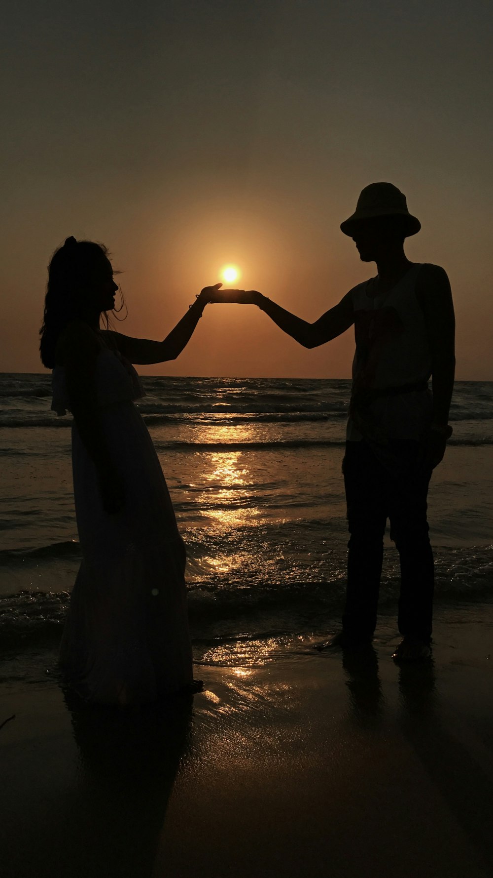 silhouette di uomo e donna che si baciano sulla spiaggia durante il tramonto