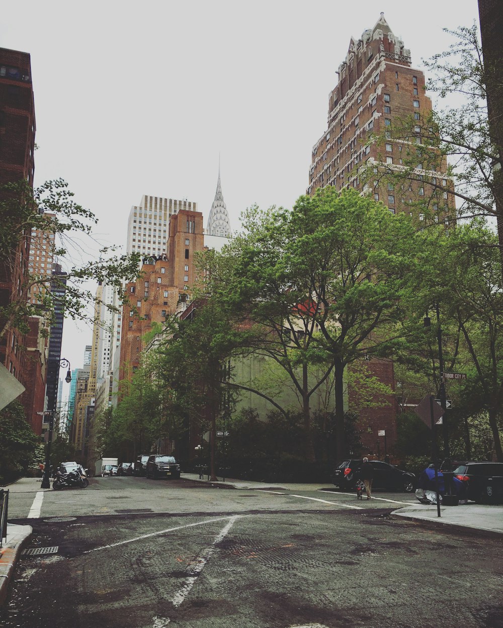 cars parked on sidewalk near high rise buildings during daytime