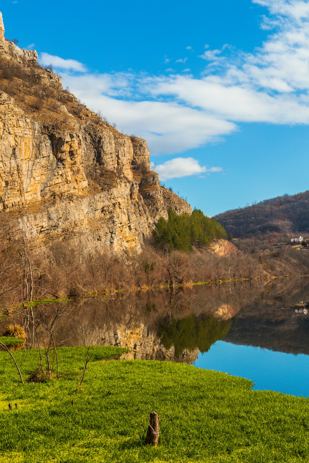 brown rocky mountain beside river under blue sky during daytime