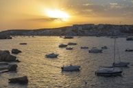 A picturesque view of the Sanlúcar coastline at sunset, with sailboats gently floating on the water.