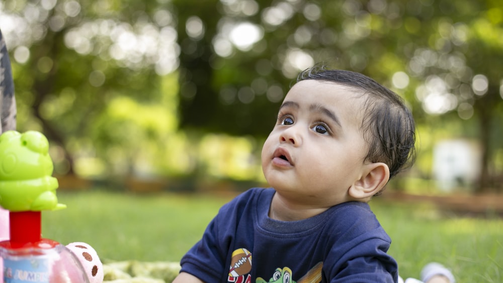 boy in blue crew neck t-shirt lying on green grass during daytime