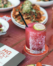 clear drinking glass with red liquid and black straw on red table