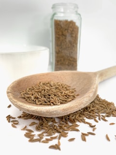 Close-up of golden cumin seeds spilling from a rustic burlap sack on a wooden table