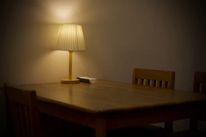 A sleek wooden dining table set with matching chairs in a warmly lit room.
