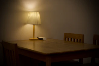 Wooden dining table with matching chairs in a warmly lit room.