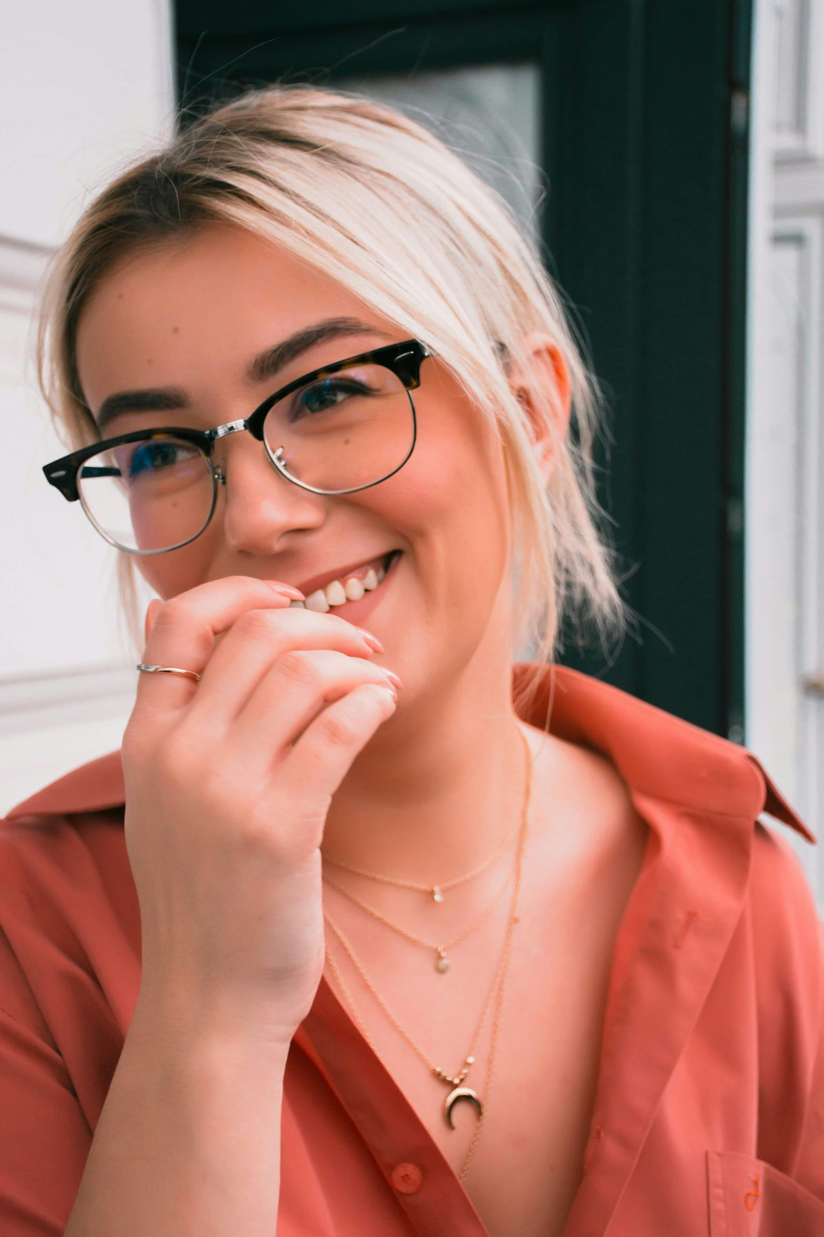 woman in orange coat wearing black framed eyeglasses