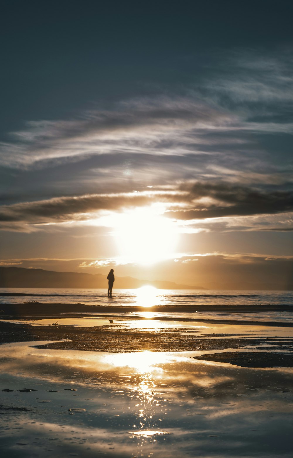 夕暮れ時の浜辺に立つ人のシルエット