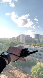 A professional using a sleek two-way radio in an outdoor work setting.