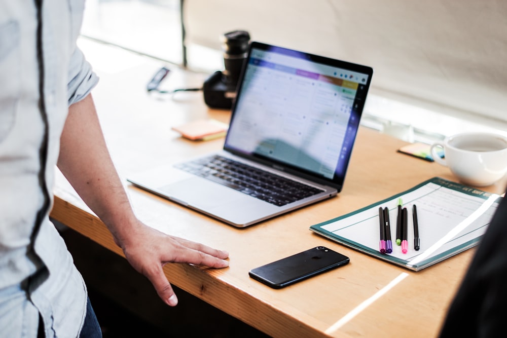 Persona che usa MacBook Pro su un tavolo di legno marrone