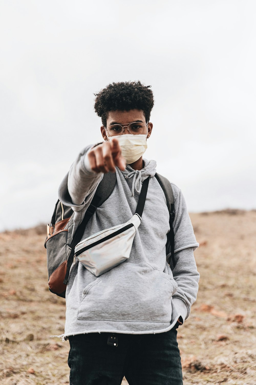 man in gray hoodie covering his face with his hand