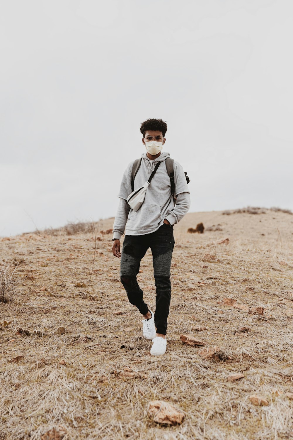 man in gray hoodie and black pants standing on brown grass field during daytime