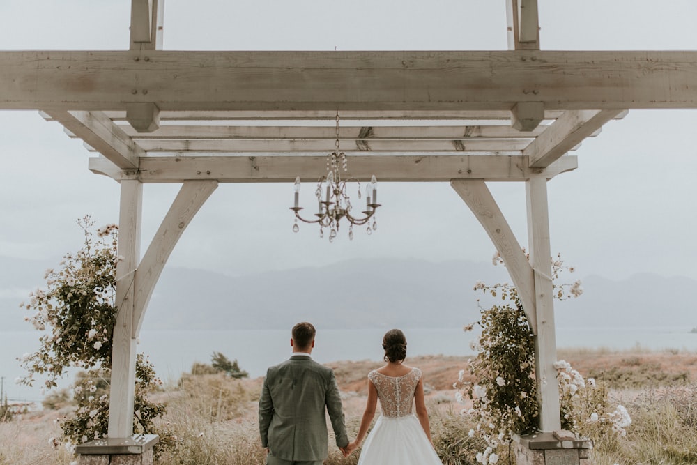 man and woman standing under white wooden cross