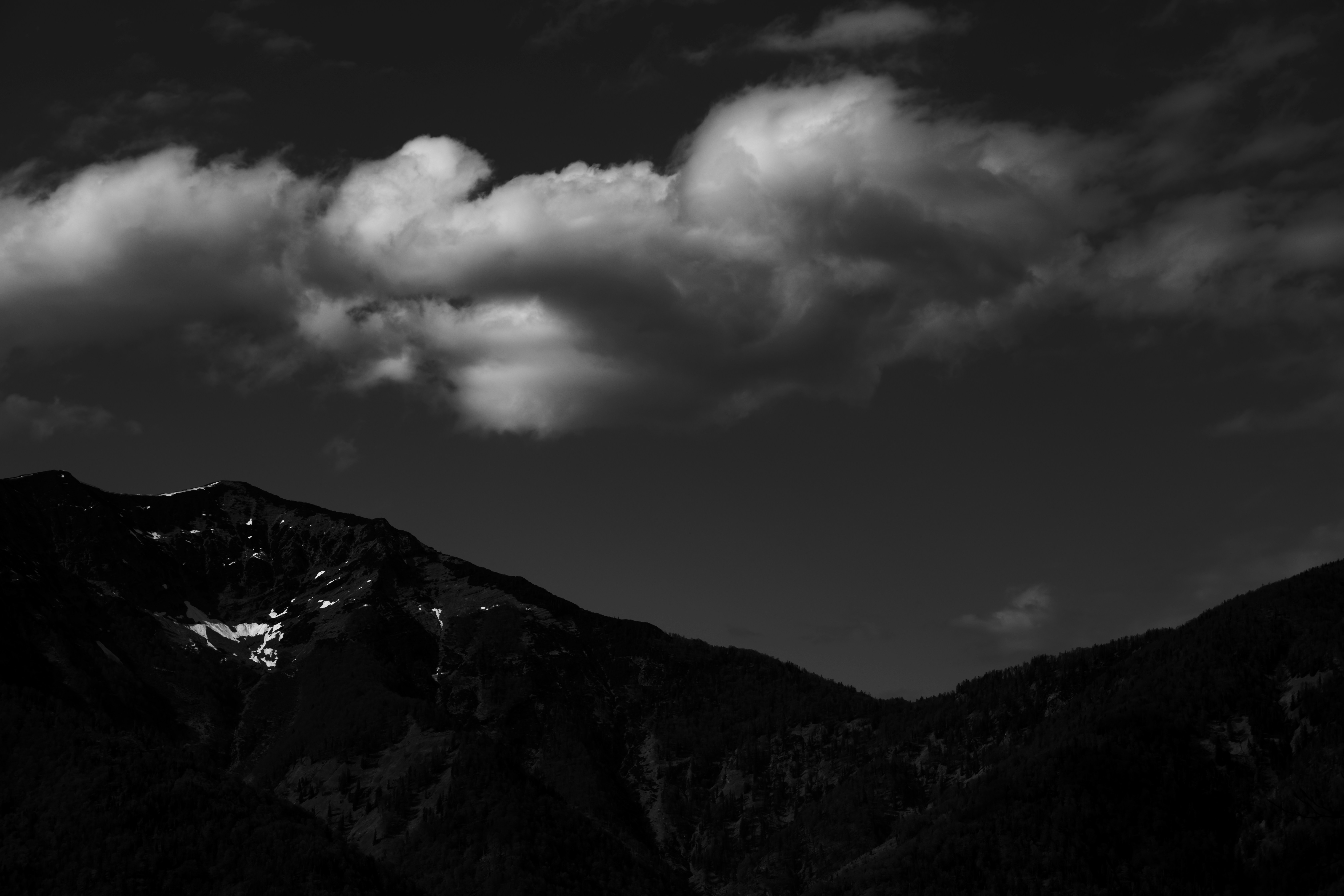 grayscale photo of mountains under cloudy sky