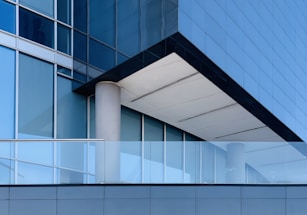 white concrete pillar near blue glass window