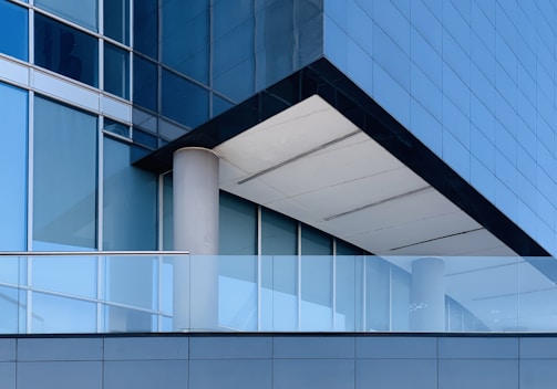 white concrete pillar near blue glass window