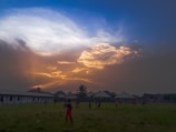 Children playing soccer on a grassy field near the old family church at sunset.