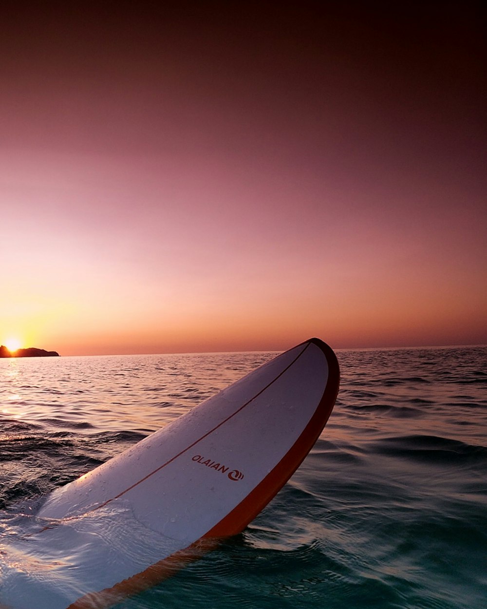 white and blue surfboard on sea during sunset