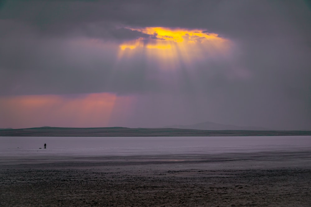 body of water under cloudy sky during sunset