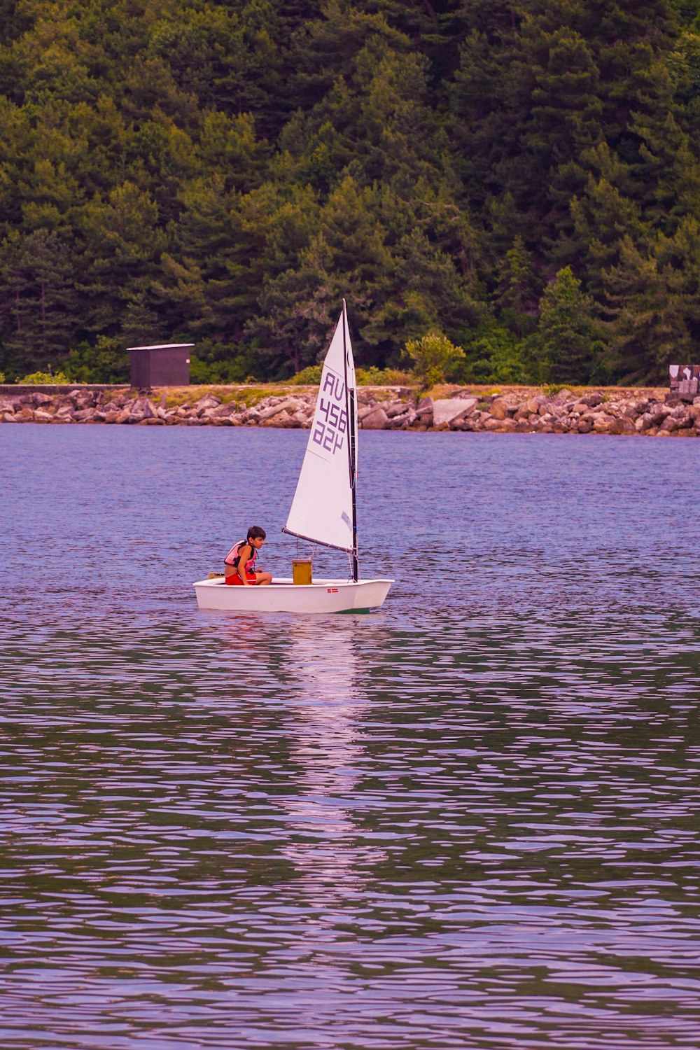 Persona che cavalca su una barca bianca e gialla sullo specchio d'acqua durante il giorno