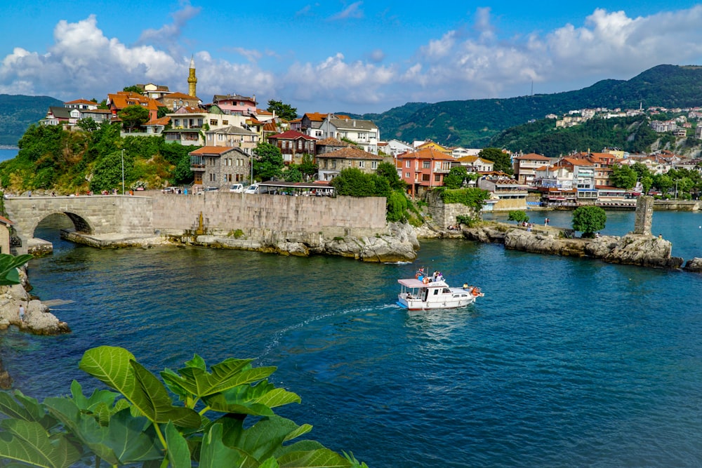 white boat on sea near city buildings under blue sky during daytime