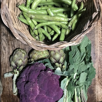 A vibrant basket overflowing with freshly harvested green vegetables on a rustic wooden table.