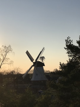A windmill turning steadily in a green field at sunset.