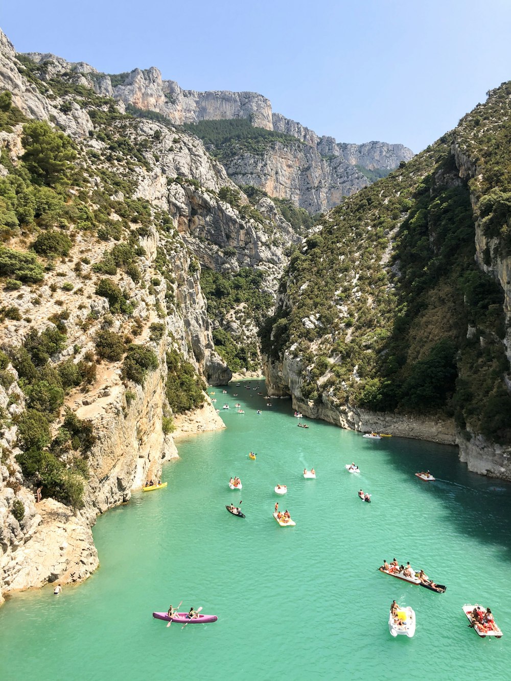 people swimming on river between mountains during daytime