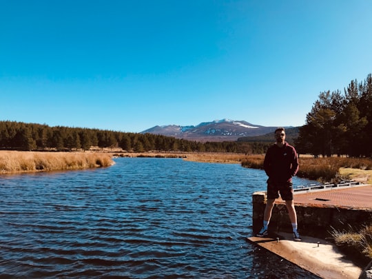 man in black jacket standing on brown wooden dock during daytime in Cairngorms National Park United Kingdom