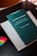 A book with a dark green cover is titled 'Iusnaturalismo y Positivismo Jurídico' by Norberto Bobbio is placed on top of a light-colored folder or book. There are colorful sticky note markers in pink, yellow, green, and blue on a dark surface next to the book.