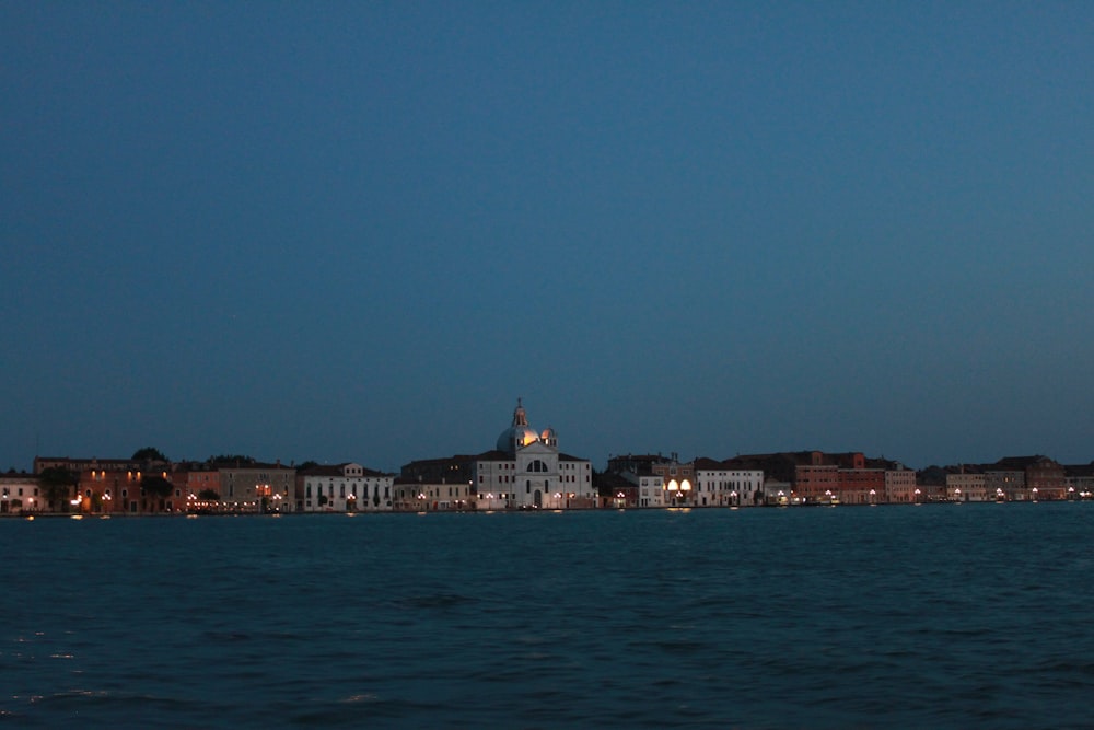 city skyline across body of water during night time