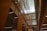 A modern interior featuring high ceilings and rows of glass-panelled walls, creating a spacious, well-lit corridor. The architectural design incorporates clean lines, with balconies and lighting fixtures enhancing the sense of openness.