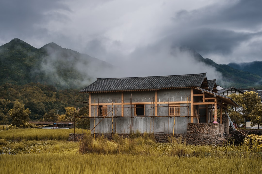 brown wooden house on green grass field under gray clouds