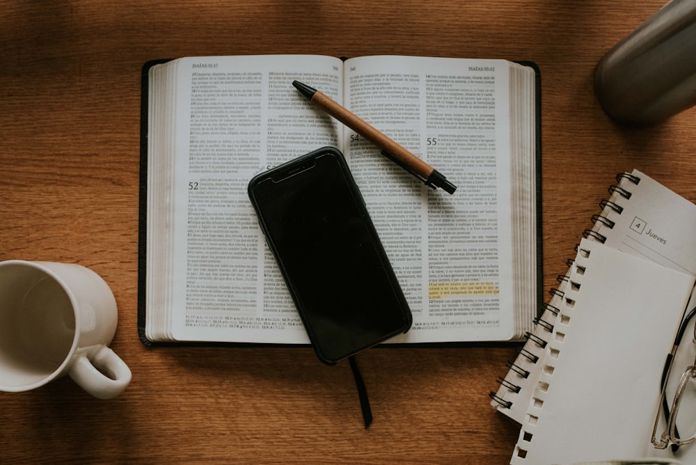 black smartphone on white notebook