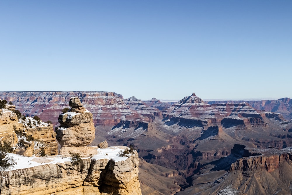 man in black jacket sitting on brown rock formation during daytime