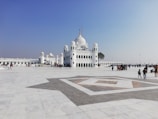 people walking on street near white concrete building under blue sky during daytime